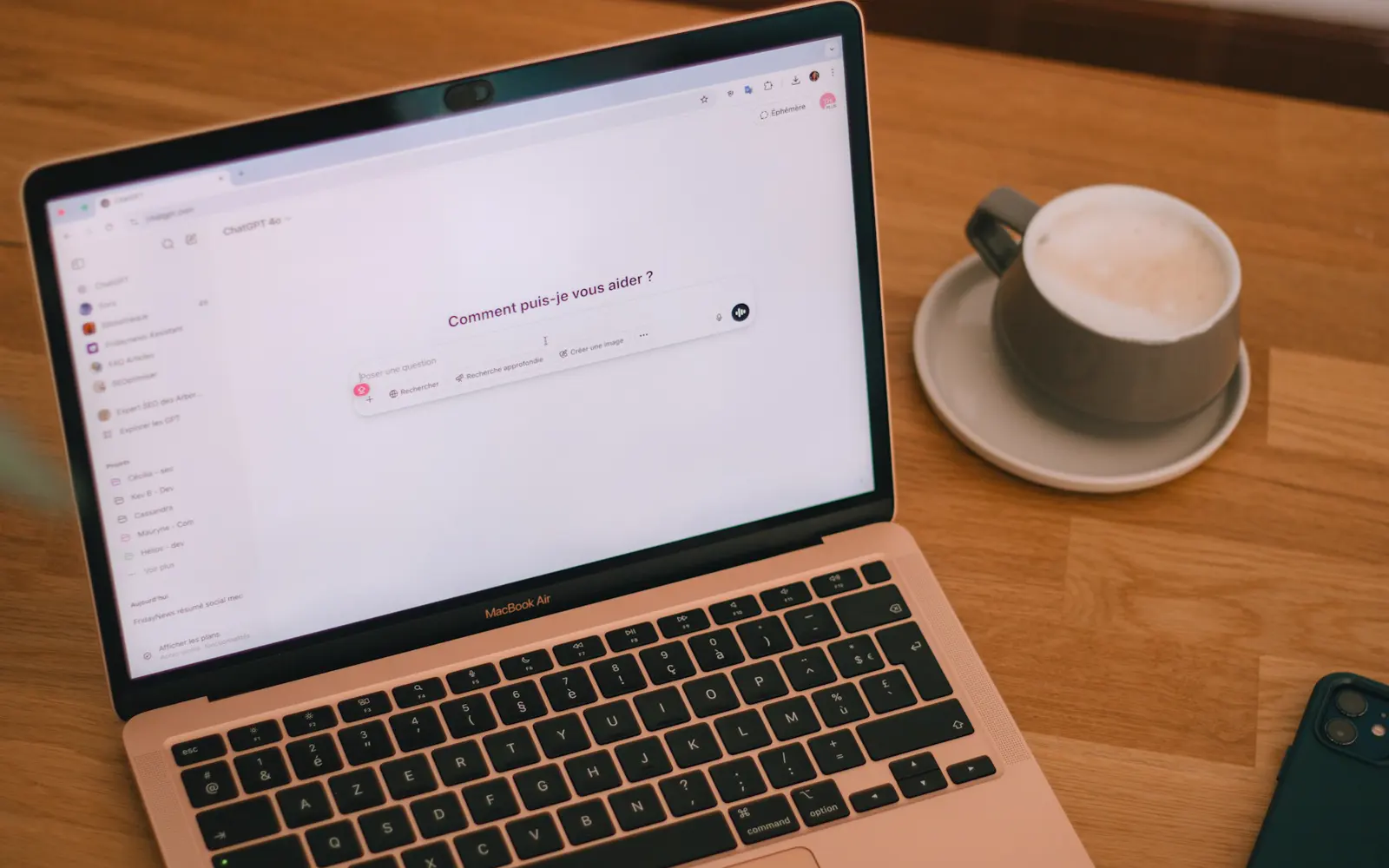 Ordinateur portable ouvert sur un assistant d'intelligence artificielle en français, posé sur une table en bois