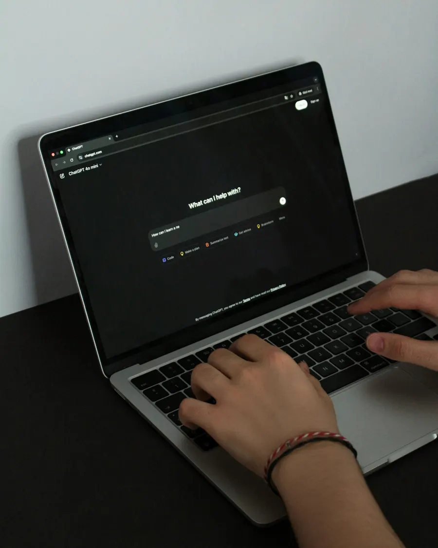 Mains sur le clavier d'un ordinateur portable ouvert sur un assistant d'intelligence artificielle