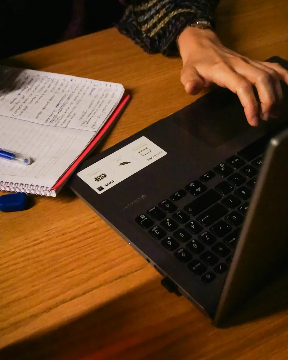Prise de notes manuscrites à côté d'un ordinateur portable, sur un plan de travail en bois